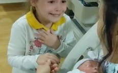 As soon as the little girl sees her newborn sister for the first time in her mother's arms, she begins to cry with joy.